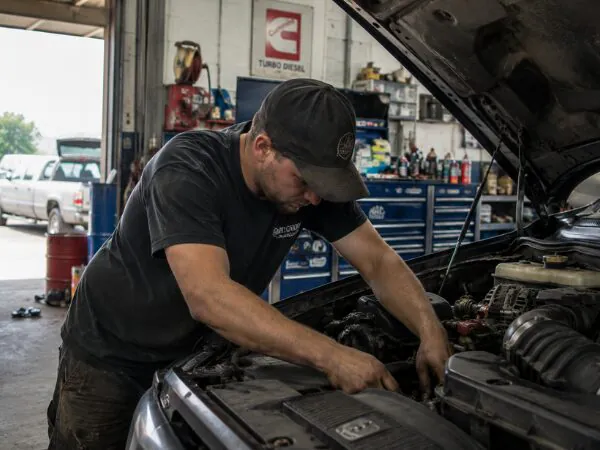 Mechanic working on an engine under an open hood