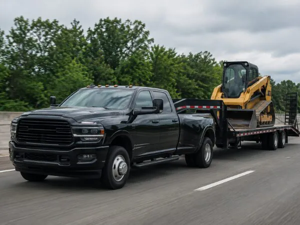 Heavy-duty pickup truck towing a trailer loaded with a skid steer